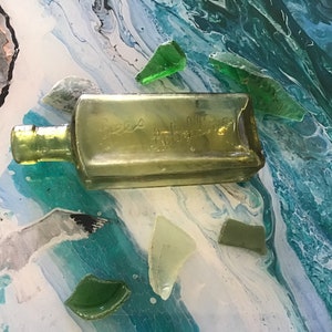 Una botella verde inusual con "Gees Lobelline" en relieve en el costado