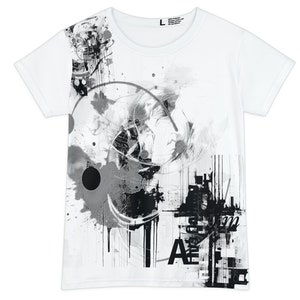 May include: White t-shirt featuring a black and grey abstract artwork. The design incorporates splatters, drips, and geometric forms, with the letters "A" and "E" visible. Made from 100% polyester, the shirt is labelled size "L".