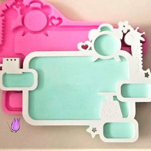 May include: A pink and white silicone mould for resin art. The mould features a rectangular frame with a light blue centre, adorned with clock, star, and giraffe designs. The background is a solid pink colour.