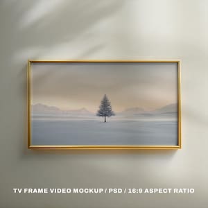 May include: A framed landscape print featuring a solitary evergreen tree in a snowy field, with mountains in the background. The artwork is set within a gold-colored rectangular frame. The text at the bottom reads "TV FRAME VIDEO MOCKUP / PSD / 16:9 ASPECT RATIO".