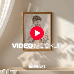 May include: A framed art print with a gold-colored frame, featuring a watercolor illustration of a woman holding a baby. The words "VIDEO MOCKUP" are displayed in white text. The bottom of the frame displays the text "FRAME ART WONDERLAND".