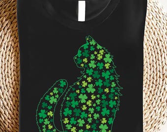 May include: Black t-shirt with a green cat silhouette made of shamrocks. The cat is sitting with its tail curled around its body.