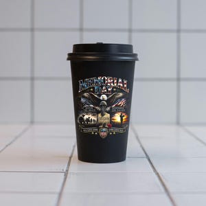 May include: Black travel mug with a black lid. The mug features a patriotic design with an eagle, American flag, and the words "Memorial Day," "Freedom," and "Honor the Brave." The design includes the text "All Gave Some, Some Gave All."