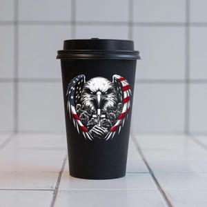 May include: Black reusable coffee cup with a graphic of a bald eagle with wings spread, holding a cross. The eagle is surrounded by a red, white, and blue American flag design.
