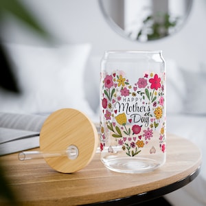 May include: A clear glass can with a bamboo lid and a straw. The can has a floral design with the text "Happy Mother's Day" in a heart shape.