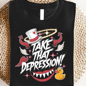 Puede incluir: Camiseta negra con un diseño gráfico que presenta un diablo, un ángel, un sombrero de copa, una boca roja y un pato de goma amarillo. El texto "Take That Depression!" está escrito en blanco.