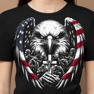May include: Black t-shirt with a graphic of a bald eagle with outstretched wings, a cross, and soldiers praying. The eagle's wings are formed by the American flag.