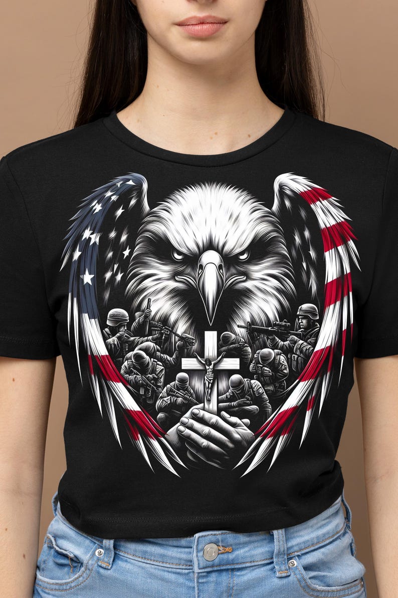 May include: Black t-shirt with a graphic of a bald eagle with outstretched wings, a cross, and soldiers praying. The eagle's wings are formed by the American flag.