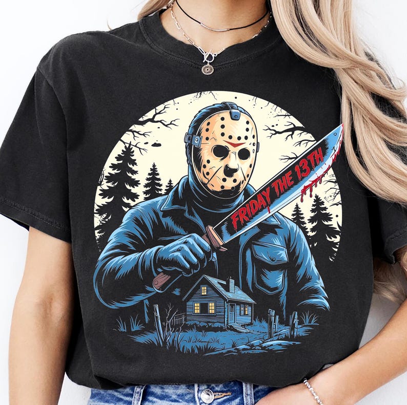 May include: Black t-shirt featuring a graphic of a masked figure holding a bloody knife with the text "FRIDAY THE 13TH". The design includes a house, trees, and a full moon, creating a horror movie theme.