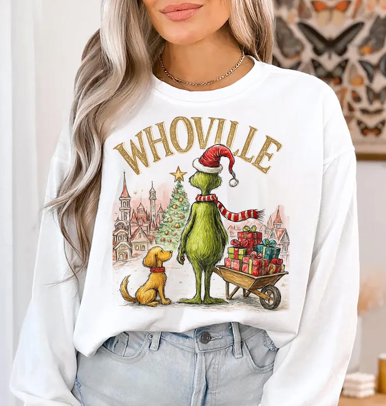 May include: White long-sleeve sweatshirt featuring a whimsical illustration of the Grinch in a Santa hat and scarf, with a dog and gifts. The word "WHoville" is printed above the Grinch. A Christmas tree and buildings are in the background.