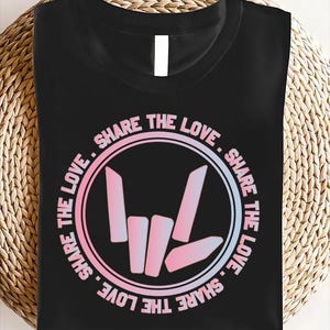 May include: Black t-shirt with a pink and blue logo that says "Share the Love" in a circle around a hand gesture.