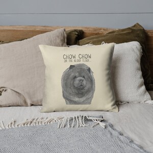 May include: A throw pillow with a cream background and a black and white illustration of a Chow Chow dog. The text "Chow Chow or the aloof floof..." is printed above the dog.