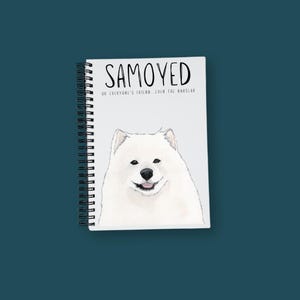 May include: A white spiral bound notebook with a white Samoyed dog illustration on the cover. The text "SAMOYED" is written in black above the dog and "OR EVERYONE'S FRIEND, EVEN THE BURGLAR" is written in black below the dog.