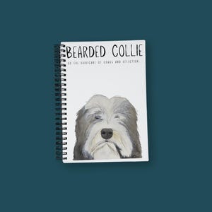 Pode incluir: Um caderno branco de espiral com uma ilustração em preto e branco de um cão bearded collie. O texto na capa diz "Bearded Collie or the hairricane of chaos and affection..."