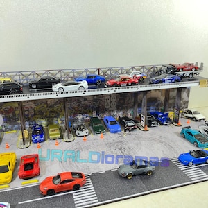 May include: A miniature city scene with a multi-level parking garage and a variety of toy cars in different colors, including red, blue, white, black, and yellow. The cars are parked on the different levels of the garage and on the street below.