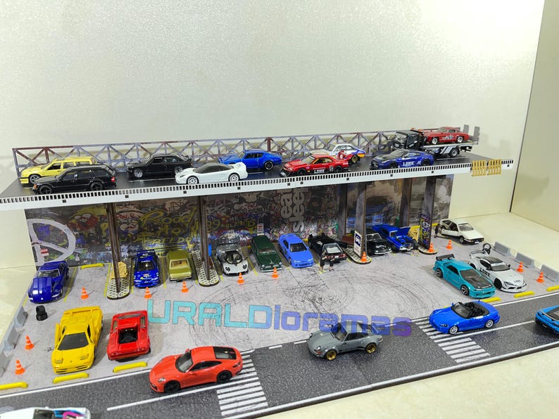 May include: A miniature city scene with a multi-level parking garage and a variety of toy cars in different colors, including red, blue, white, black, and yellow. The cars are parked on the different levels of the garage and on the street below.