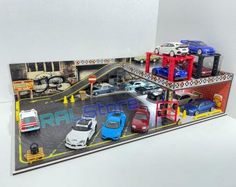 May include: A multi-level toy garage with a red and white lift, a ramp, and a variety of toy cars in different colors, including blue, white, and red. The garage is made of wood and has a black and white street scene on the front.