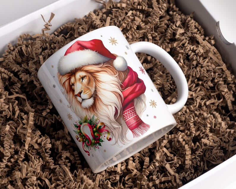 Puede incluir: Taza de cer&aacute;mica blanca con un dise&ntilde;o festivo que presenta un le&oacute;n con un gorro de Pap&aacute; Noel y una bufanda roja. El le&oacute;n tiene una corona de flores verde alrededor del cuello con una herradura dorada y cintas rojas. La taza tiene un asa blanca y un fondo blanco con copos de nieve y estrellas doradas.