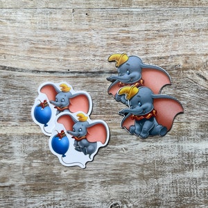 May include: Four stickers featuring Dumbo the elephant from Disney's Dumbo. Two stickers show Dumbo holding a blue balloon and two stickers show Dumbo with his ears spread out.