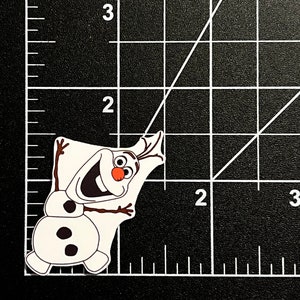 Puede incluir: Un mu&ntilde;eco de nieve blanco con una nariz de zanahoria, ojos negros y botones. Sonr&iacute;e con los brazos extendidos y lleva un sombrero de rama marr&oacute;n.