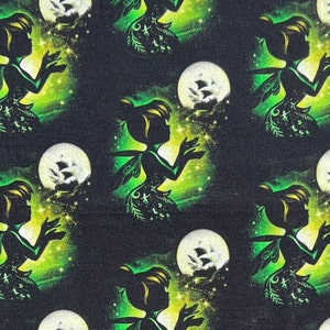 May include: A black fabric with a repeating pattern of a green fairy silhouette holding a white moon with a ship design. The fairy is surrounded by green and yellow stars.