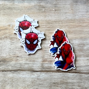 May include: Several Spider-Man stickers. Two stickers feature Spider-Man's mask breaking through a wall. The other two stickers show Spider-Man in a crouching pose, with red and blue suit details.