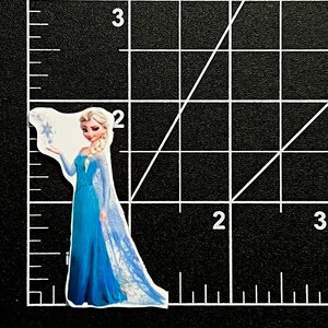 Puede incluir: Un personaje azul y blanco de la pel&iacute;cula Frozen, sosteniendo un copo de nieve en su mano. Lleva un vestido azul con una capa blanca y tiene el pelo largo y rubio.