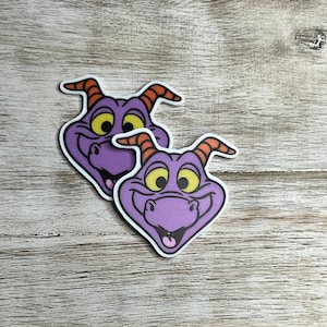 May include: Two purple and orange cartoon dragon stickers with a smiling face.