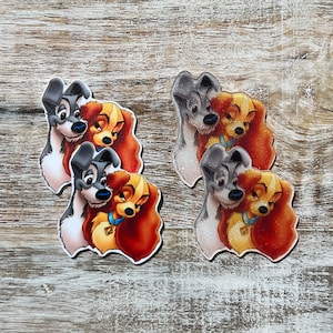 May include: Two sets of cartoon dog characters, Lady and the Tramp, in a close-up view. The characters are depicted in a loving embrace, with Lady's brown fur and Tramp's gray fur visible. The characters are printed on a white background.