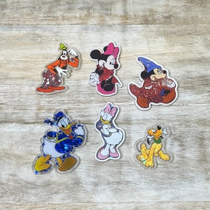 May include: Six colorful character stickers featuring Disney characters like Mickey Mouse, Minnie Mouse, Donald Duck, Goofy, and Pluto. The stickers are made of glitter and have a glossy finish.