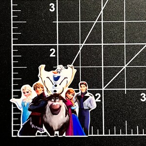 Puede incluir: Una pegatina con los personajes de la pel&iacute;cula Frozen. La pegatina muestra a Elsa, Anna, Kristoff, Olaf y Sven. Los personajes est&aacute;n de pie frente a un fondo azul y blanco.