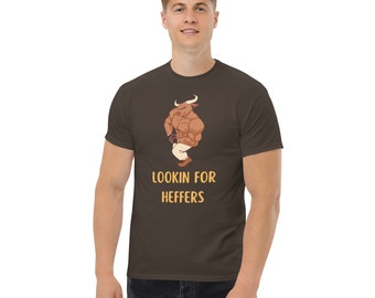 May include: A brown t-shirt with a cartoon image of a muscular bull wearing pants and holding a cup. The text "LOOKIN FOR HEFFERS" is printed in yellow below the image.