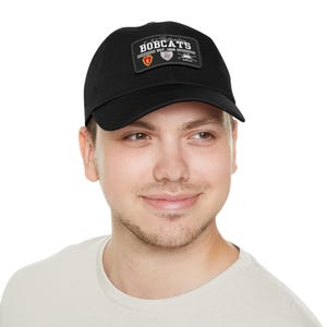 May include: A black baseball cap with a patch that says "Ft. Jackson Bobcats Est. 1908" with a red and white logo.
