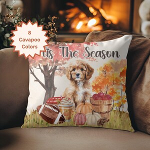 May include: A square throw pillow featuring a watercolor illustration of a Cavapoo puppy surrounded by autumn elements including a football, a coffee cup, pumpkins, and a bucket of apples. The text 'Tis The Season' is printed above the puppy.