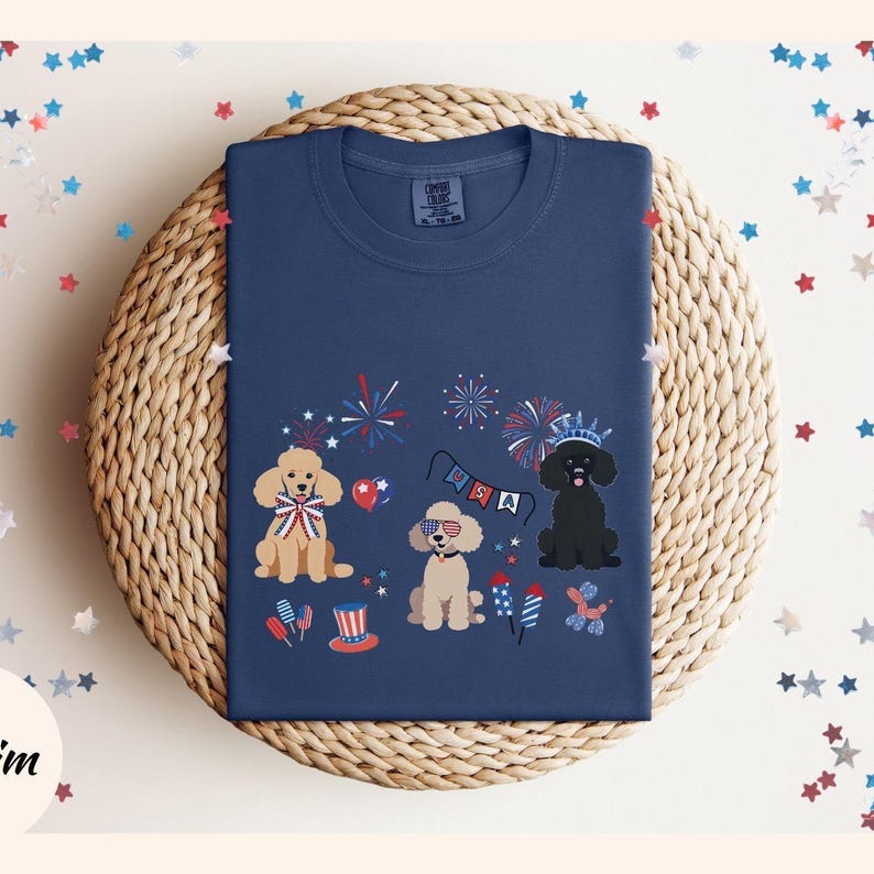 May include: Navy blue t-shirt with a patriotic design featuring three poodles wearing red, white, and blue accessories. The design includes fireworks, stars, and the words "USA".