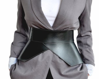 May include: A gray blazer with a black leather belt. The belt is wide and has a unique, angled design.
