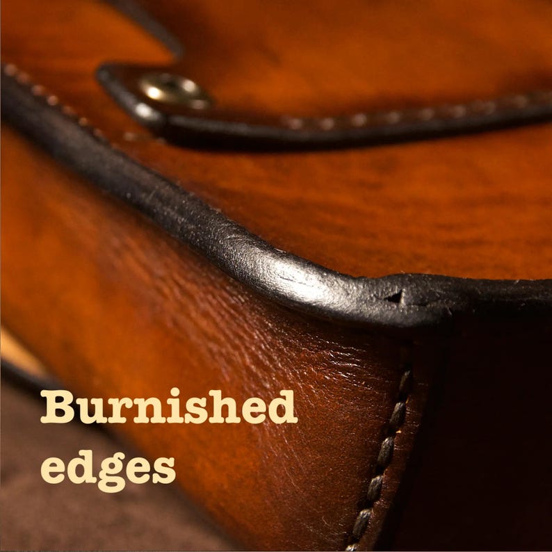 May include: Close-up of a leather item with a rich, brown color and a polished finish. The edges are dark and well-defined, with visible stitching. The text "Burnished edges" is displayed in a bold, serif font.