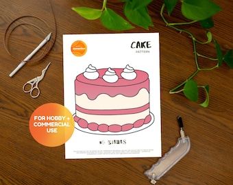 May include: A printable cake pattern for crafting. The pattern shows a pink and white cake with three white frosting swirls on top. The text "CAKE PATTERN" is at the top of the page. The text "FOR HOBBY + COMMERCIAL USE" is in a circle at the bottom left of the page. The text "#5 EIDORS" is at the bottom center of the page.