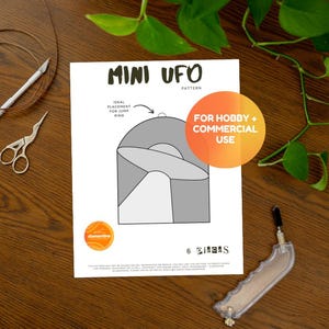 May include: A printed pattern sheet with a UFO design, ideal for jump rings. The sheet includes the text "MINI UFO PATTERN" and "FOR HOBBY + COMMERCIAL USE". Also visible are craft tools, including scissors and a craft knife.