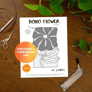 May include: A printed pattern titled "BOHO FLOWER" with a floral design in grey and white. The image includes a pair of scissors, a craft knife, and a tool, all on a wooden surface. Text on the image says "FOR HOBBY + COMMERCIAL USE."