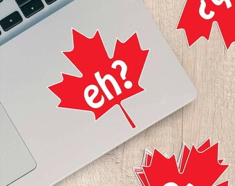 May include: Red maple leaf sticker with the word "eh?" in white. The sticker is on a laptop. Additional stickers with the same design are scattered around the laptop.