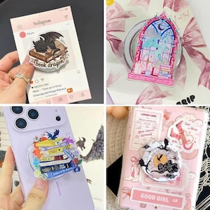 May include: A collection of four circular phone grips featuring various illustrations including a dragon sleeping on books, a dragon in a stained glass window, a stack of colorful books, and a sun with silhouettes of dragons and clouds.