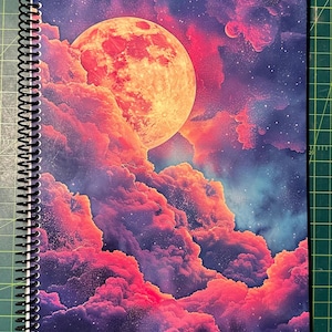 May include: Spiral-bound notebook featuring a vibrant illustration of a celestial scene. The cover showcases a large, orange-red moon set against a backdrop of pink and purple clouds, with a starry sky. The notebook's binding is black.