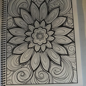 Puede incluir: Una p&aacute;gina para colorear en blanco y negro con un dise&ntilde;o de mandala detallado con una gran flor en el centro rodeada de patrones en espiral.