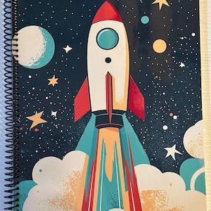 May include: Spiral-bound notebook featuring a colorful illustration of a rocket ship blasting off into space. The design includes a white rocket with red fins, a blue and white planet, stars, and a dark blue starry background.