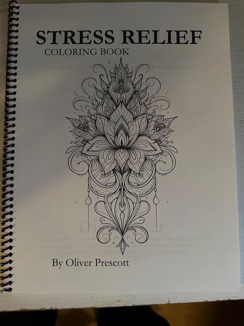 Puede incluir: Un libro para colorear en blanco y negro titulado "Stress Relief Coloring Book" de Oliver Prescott. La portada presenta un dise&ntilde;o floral intrincado.