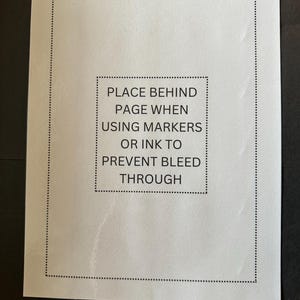 K&ouml;nnte beinhalten: Ein wei&szlig;es Blatt Papier mit einem schwarzen Rand und dem Text "PLACE BEHIND PAGE WHEN USING MARKERS OR INK TO PREVENT BLEED THROUGH" in der Mitte.