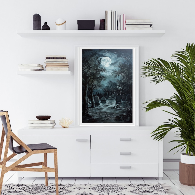 May include: A painting of a moonlit graveyard with a full moon in the sky. The trees are silhouetted against the moon and the tombstones are scattered throughout the graveyard. The painting is framed in a white frame.