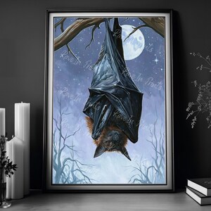 May include: A framed print of a bat hanging upside down from a tree branch. The bat is black with brown fur and is set against a night sky with a full moon and bare trees. The artwork has a gothic or Halloween theme.