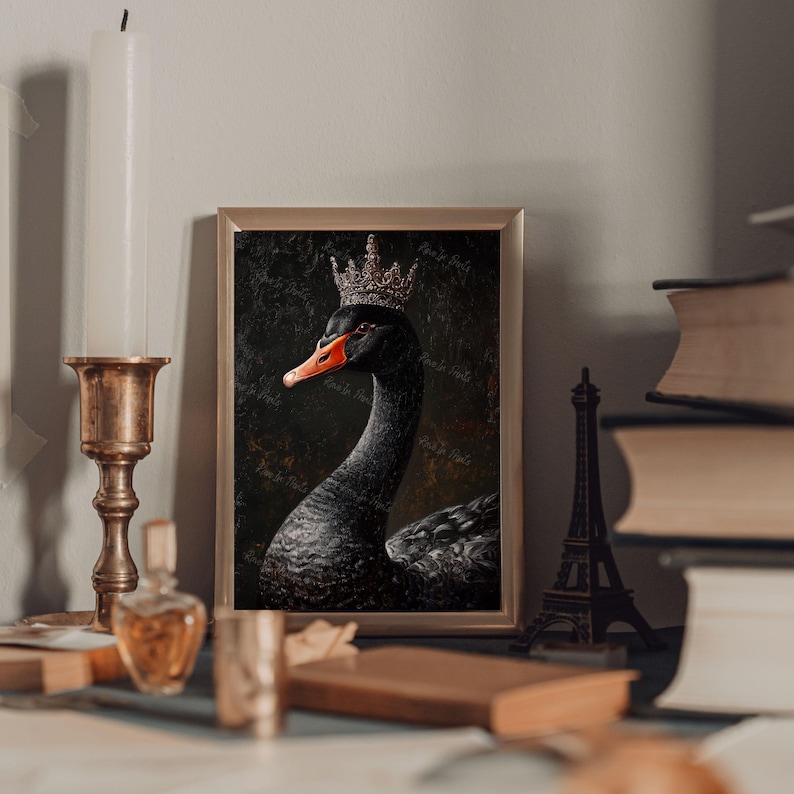 Pu&ograve; includere: Stampa artistica incorniciata raffigurante un cigno nero con una corona. Il cigno ha un becco arancione ed &egrave; in una cornice dorata. L'opera d'arte &egrave; esposta su un tavolo con altri oggetti decorativi.